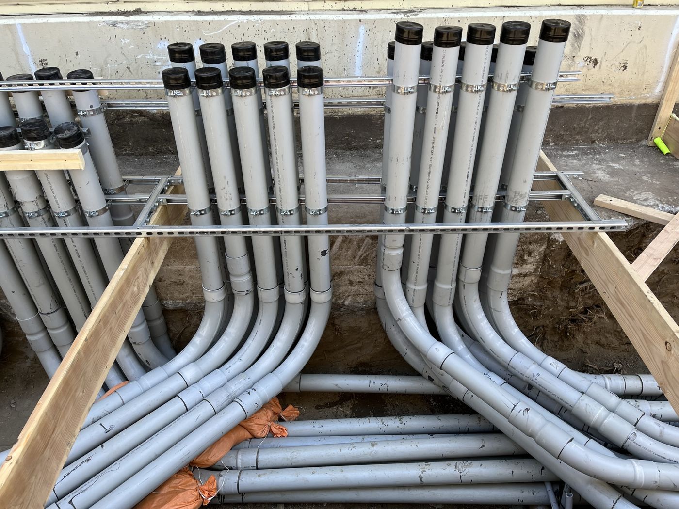 Banks of PVC conduit sweeping up out of the trench into stub-ups racked on strut